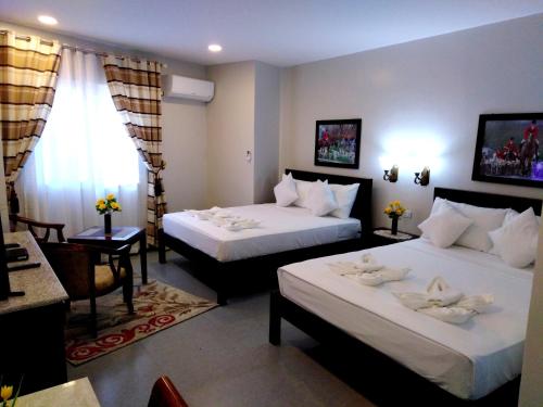 伊洛伊洛Venezia Suites Hotel Iloilo的酒店客房设有两张床和窗户。