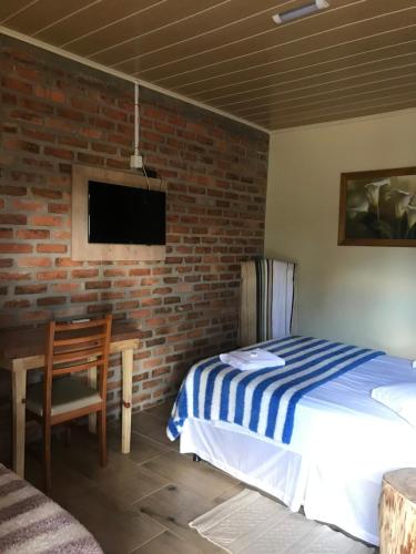 VacariaPOUSADA DAS PIPAS的一间卧室设有一张床和砖墙
