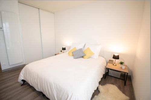 普瓦西Joli studio tout confort à 2 pas de la gare Poissy的卧室配有一张白色大床和一张边桌