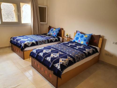 艾因苏赫纳Cozy chalet in a luxurious compound family only的一间卧室配有两张带蓝色棉被的床
