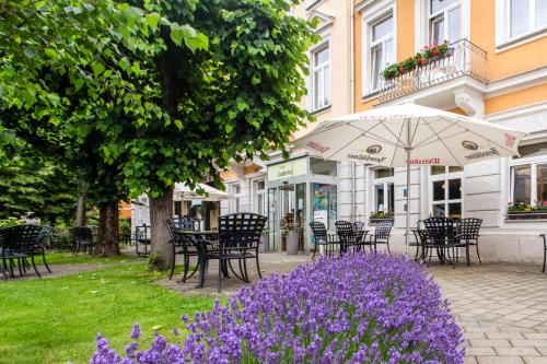 巴特尚道林登霍夫巴德施德酒店的一组桌椅和紫色的鲜花