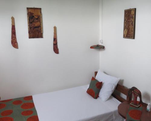 圣多美Micaval Residential的一间白色的卧室,配有一张床和墙上的一些照片