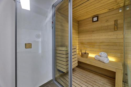 卡门港THB花卉酒店的一间铺有木地板并配有玻璃门的桑拿浴室