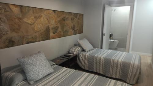 梅里达Alcazaba - Free Parking的一间卧室设有两张床和岩石墙