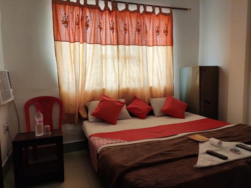 阿格拉格蕾丝酒店  的一间卧室配有一张带红色枕头的床和一扇窗户
