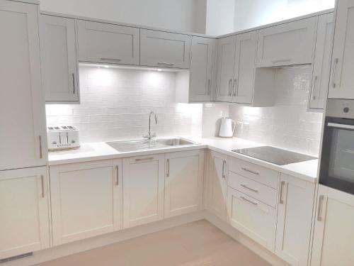 哈沃斯Haworth Hideaway的白色的厨房配有白色橱柜和水槽