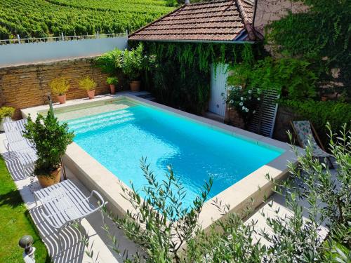 BurgyLa petite madeleine - Chambre d'hôtes & spa的享有带2把白色椅子的游泳池的顶部景致