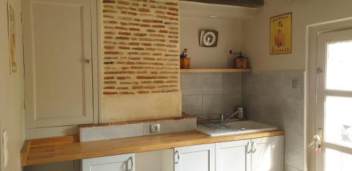 圣艾尼昂La petite maison的厨房设有水槽和砖墙