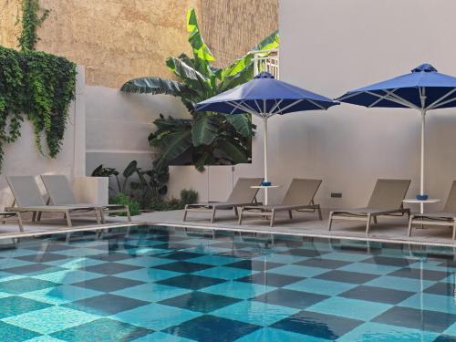 罗德镇Esperia City Hotel的一座带椅子和遮阳伞的游泳池位于一座建筑旁边