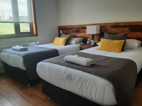蓬塔阿雷纳斯Hostal Buenavista Patagonia的两张位于酒店客房的床,上面有黄色枕头