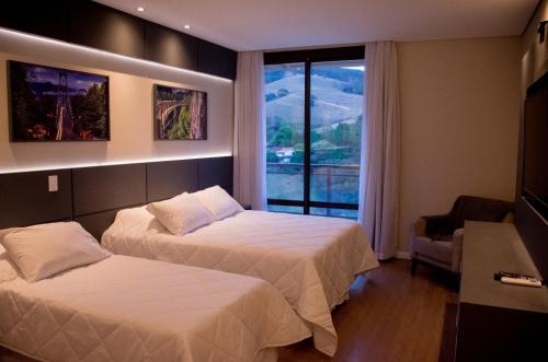 阿瓜斯迪林多亚Capitanias Hotel的酒店客房设有两张床和窗户。