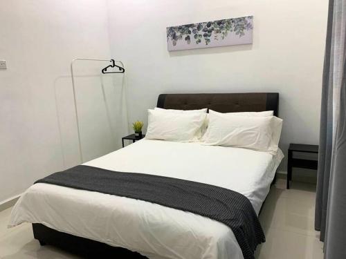 日得拉Impiana Homestay Jitra的卧室配有一张带白色床单和枕头的大床。