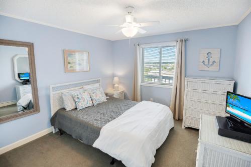 默特尔比奇2BR, 2Bath condo Oceanfront Getaway with pool的一间卧室配有一张床、镜子和电视