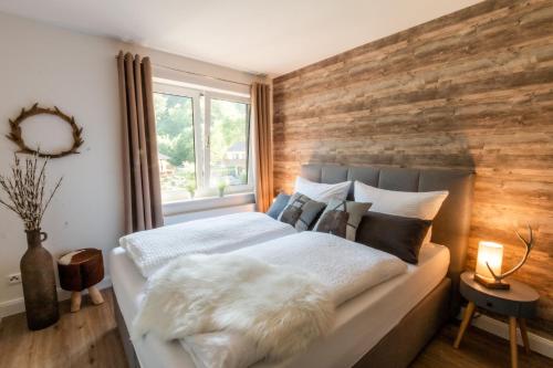韦耶达Harzfalke Apartment - Ankommen und wohlfühlen.的一间卧室设有木墙和一张床