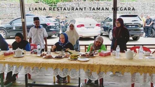 而连突Liana Hostel Taman Negara的一群人坐在桌子旁吃着食物