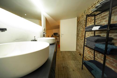 列日L'atelier de Liège: Tranquillité & Effervescence的一间带大型白色浴缸和砖墙的浴室