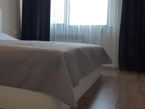 阿拉木图Квартира на речке Есентайка的一间卧室配有一张带白色床罩的床和窗户。