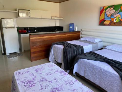 马拉戈日Flat no Caribe的带三张床和厨房的房间