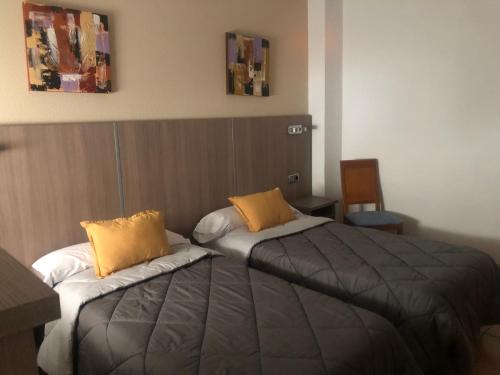 瓦尔德莫罗Hostal De La Rosa的配有黄色枕头的酒店客房的两张床