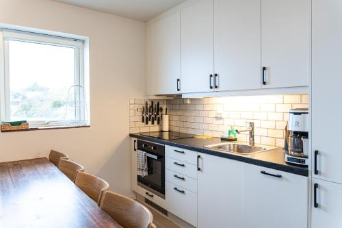 萨维兰德New Åkrahamn coast house的厨房配有白色橱柜和木桌