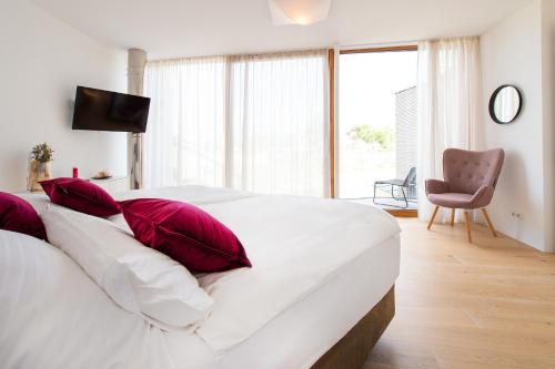 滨湖新锡德尔Seehaus SeeZeit - Am Hafen的卧室内的白色床和红色枕头