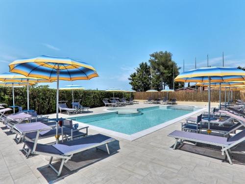 切齐纳码头Apartment Riviera 1 by Interhome的一个带蓝色和黄色遮阳伞及椅子的游泳池