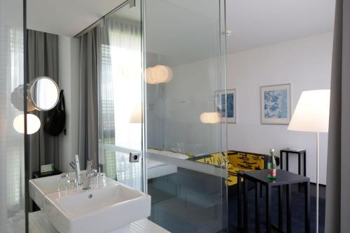 朗根洛伊斯LOISIUM Wine & Spa Hotel Langenlois的一间带水槽和玻璃淋浴的浴室