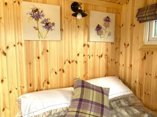 珀斯Remarkable Shepherds Hut in a Beautiful Location的一间卧室设有木墙、一张床和两张图片