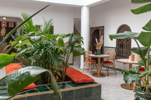 马拉喀什Riad Babouchta & Spa的一间种植了植物并配有桌椅的房间