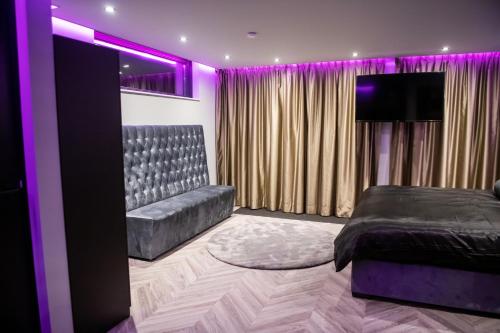 斯赫拉芬赞德Royal Suite的一间卧室配有一张床和一张沙发,拥有紫色的灯光