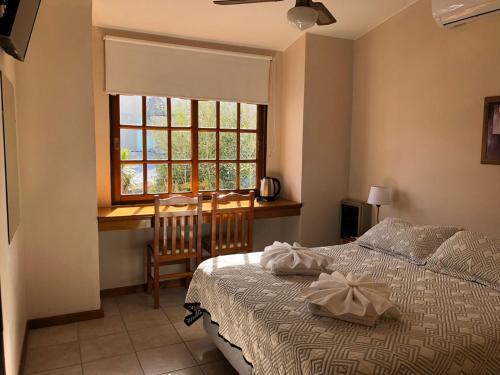 维拉卡洛斯帕兹Hotel Lihuel的一间卧室配有一张床、一张书桌和一个窗户。
