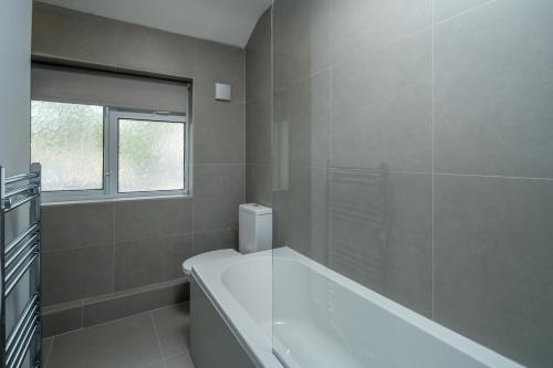 斯蒂夫尼奇Skyline Serviced Apartments - Flat B Rockingham Way的白色的浴室设有浴缸和窗户。