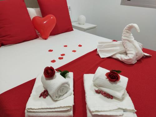 马萨龙港Apartamentos Buendía的一张带毛巾和玫瑰及心的睡床