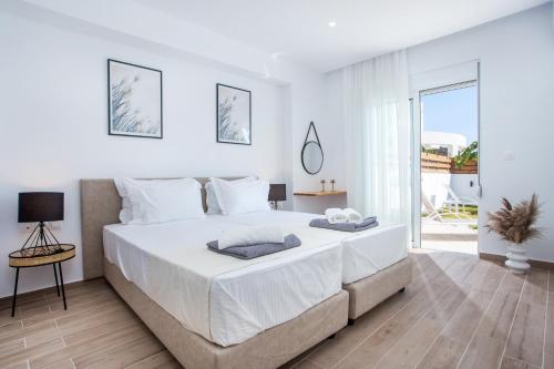 吉奥塔略Rhodian Dunes Villas的白色卧室设有一张大床和一个阳台