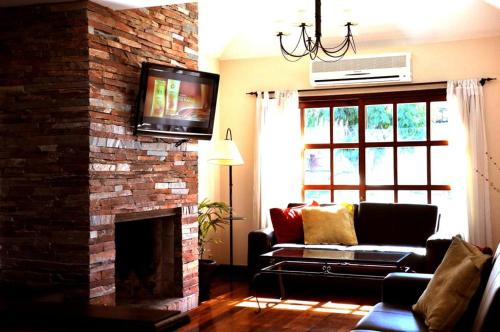 科洛尼亚-德尔萨克拉门托Ayres House的客厅配有沙发和砖砌壁炉上的电视