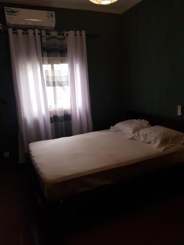 杜阿拉Superbe appartement的卧室内的一张床铺,卧室的窗户配有白色床单