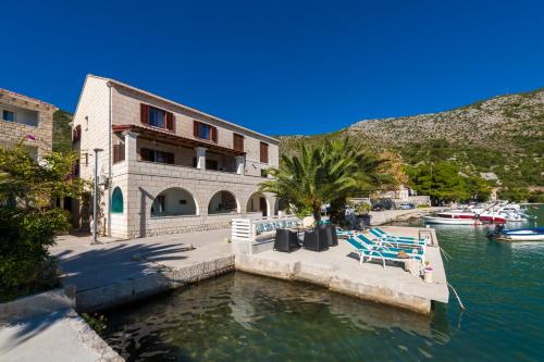 扎通Adria House Dubrovnik by the sea的毗邻水体的建筑,配有躺椅