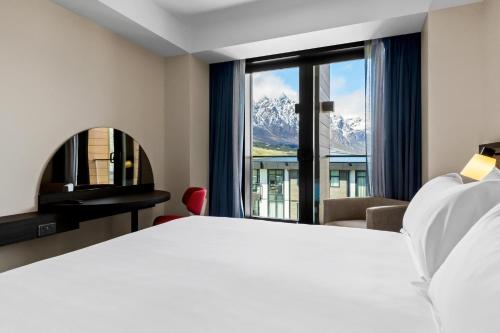 皇后镇Holiday Inn Queenstown Remarkables Park的酒店客房设有一张床和一个大窗户