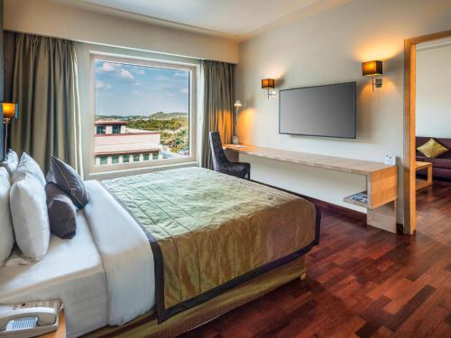 海得拉巴海得拉巴机场诺富特酒店的配有一张床、一张书桌和一扇窗户的酒店客房
