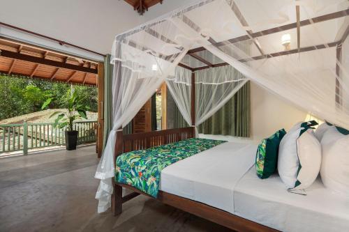 乌纳瓦图纳Green Escape Unawatuna的一间卧室设有一张天蓬床和一个阳台