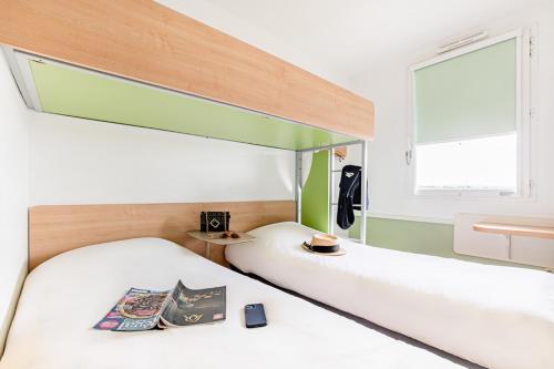 卡尔卡松ibis budget Carcassonne Aéroport - A61的一间卧室设有两张床和窗户。