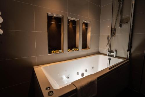 基拉卢Killaloe Hotel & Spa的带浴缸的浴室和2个窗户