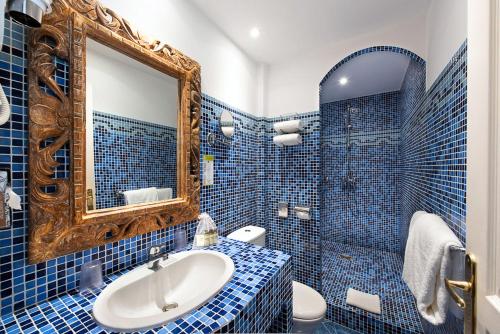 戛纳德拉图尔城堡酒店的蓝色瓷砖浴室设有水槽和镜子