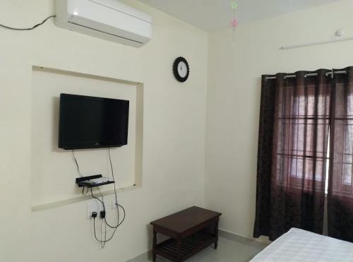 蓬蒂切里Aarudhara Holiday Home (A Home away from Home)的卧室设有壁挂式电视和桌子。
