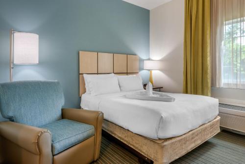 迈尔斯堡麦尔兹堡75号州际公路烛木套房酒店的一间卧室配有一张大床和一把椅子