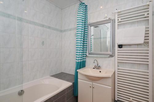 诺德克豪特De Zeemeeuw的白色的浴室设有浴缸、水槽和浴缸。
