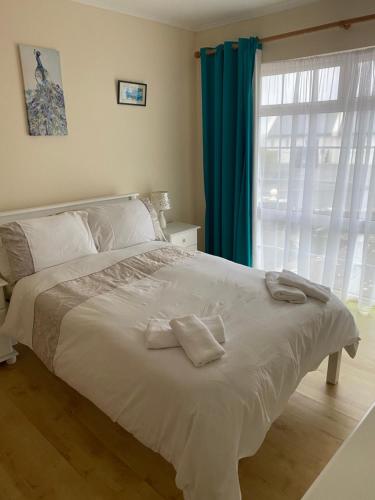 拉辛赫Cozy seaside home,3 minute walk to village/beach的卧室配有一张带蓝色窗帘的大型白色床