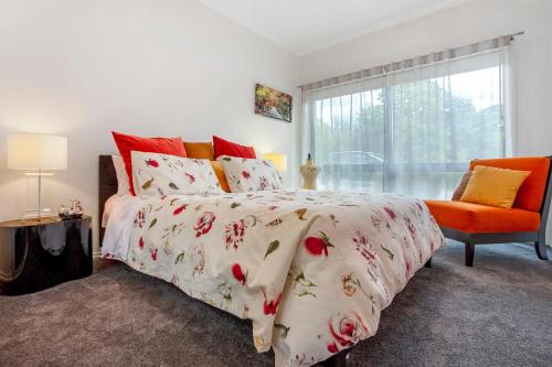 马其顿山Wotama, Macedon B and B, Honour Ave, Mount Macedon的一间卧室配有一张床和一张橙色椅子