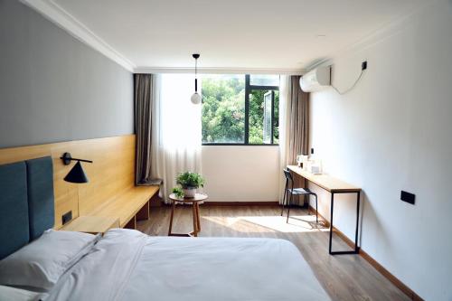 桂林桂林广湖客栈的一间卧室配有一张床、一张书桌和一个窗户。