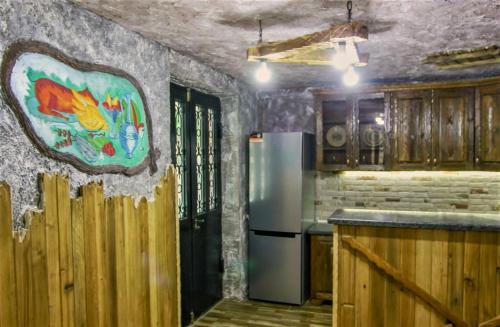 库塔伊西Mango's Guesthouse的厨房配有冰箱,墙上挂有绘画作品